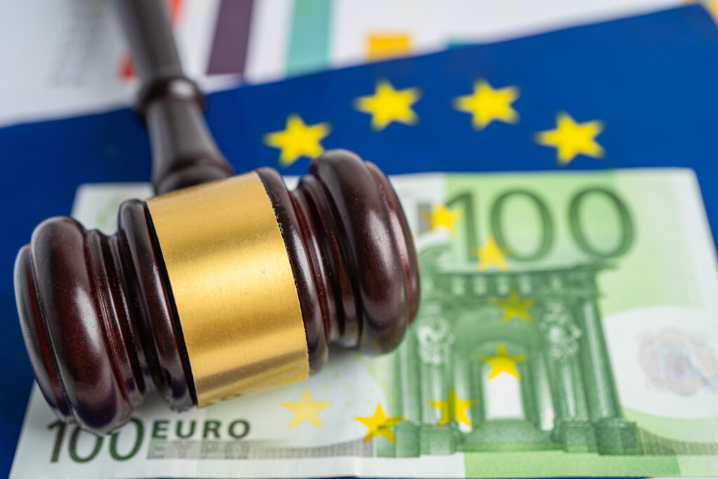 Richterhammer auf einem 100-Euro-Schein und einer EU-Flagge – Symbol für Recht, Finanzen und europäische Regulierung.