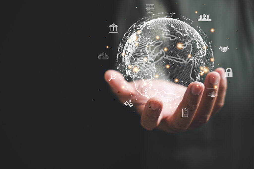 Hand hält eine digitale Weltkugel mit Netzwerken und Symbolen – Symbol für Globalisierung, internationale Strategien und Vermögensschutz.