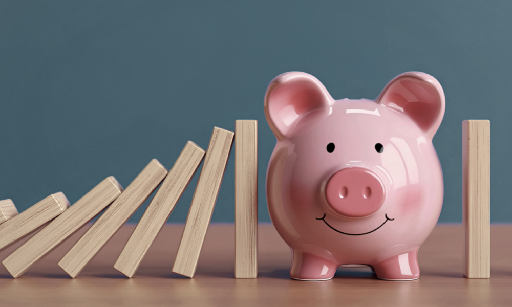 Sparschwein steht neben aufgestellten Holzklötzen, die wie eine gestoppte Kettenreaktion wirken, als Symbol für finanzielle Stabilität, Rücklagen und Liquiditätsplanung im Unternehmen