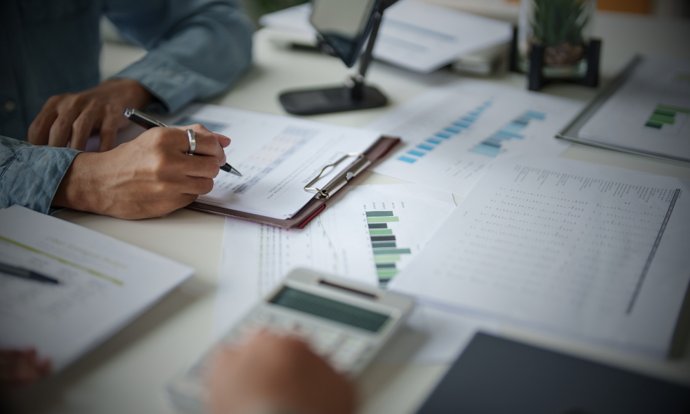 Personen prüfen Finanzunterlagen, Diagramme und Tabellen mit Taschenrechner, um Zahlungsfähigkeit und Cashflow zu analysieren; das Bild verdeutlicht das Thema „Gewinn ist nicht gleich Liquidität“