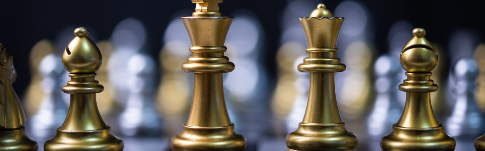 Goldene Schachfiguren auf einem Spielbrett – Symbol für Strategie, Planung und kluge Entscheidungen.