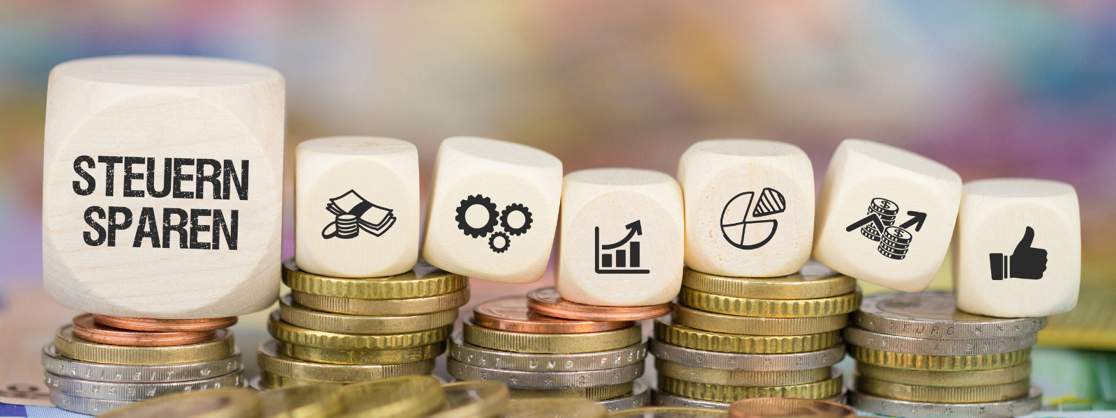 Holzwürfel mit der Aufschrift „Steuern sparen“ sowie Symbolen für Geld, Wachstum und Finanzplanung stehen auf gestapelten Münzen und veranschaulichen das Thema Steuern sparen als Selbstständiger & Freiberufler