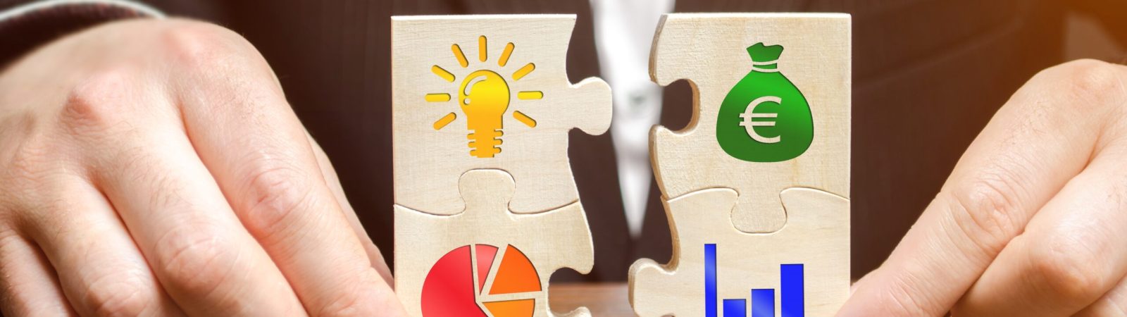 Holzpuzzle mit Symbolen für Ideen, Geld, Diagramme und Wachstum – Sinnbild für Steueroptimierung, Unternehmensstrategie und Vermögensaufbau.