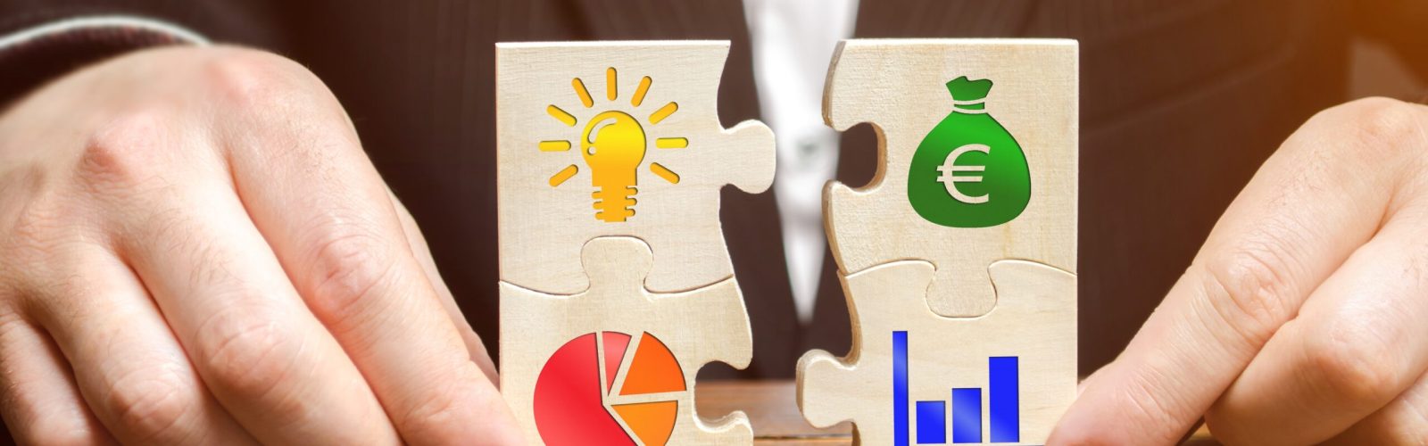 Holzpuzzle mit Symbolen für Ideen, Geld, Diagramme und Wachstum – Sinnbild für Steueroptimierung, Unternehmensstrategie und Vermögensaufbau.