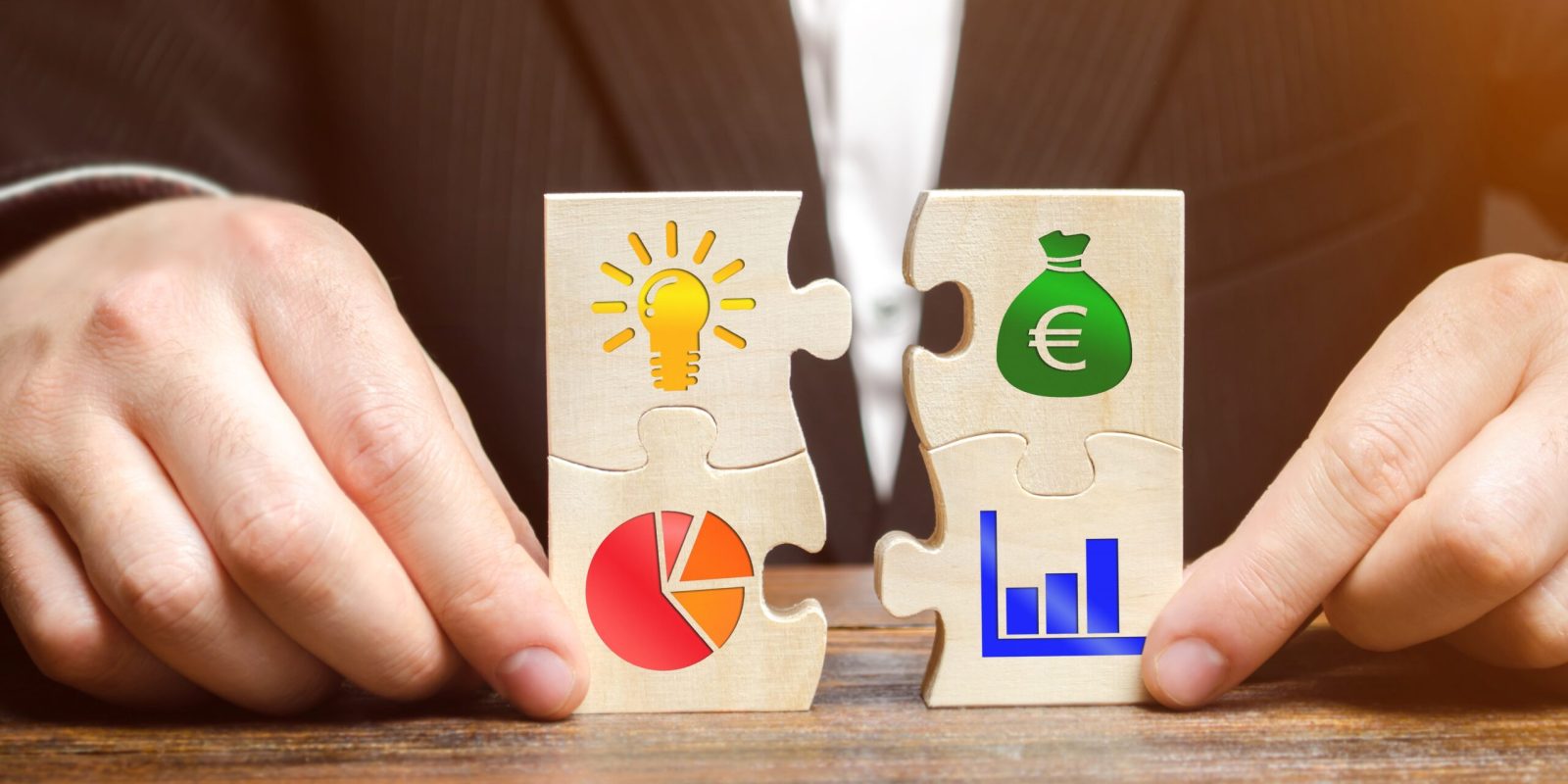 Holzpuzzle mit Symbolen für Ideen, Geld, Diagramme und Wachstum – Sinnbild für Steueroptimierung, Unternehmensstrategie und Vermögensaufbau.